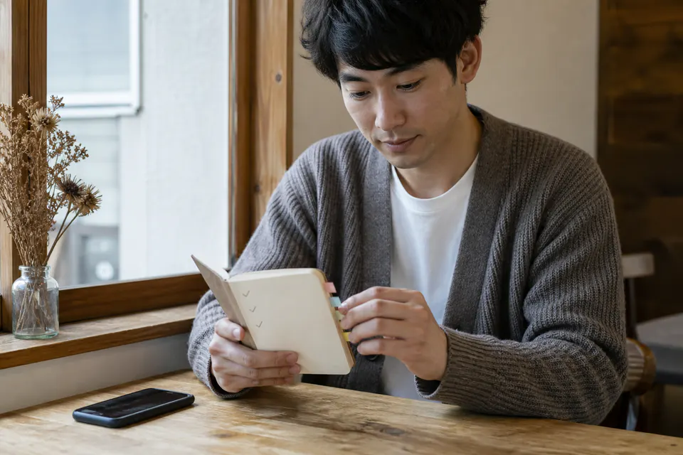 質問をまとめた小さなノートを見直す男性