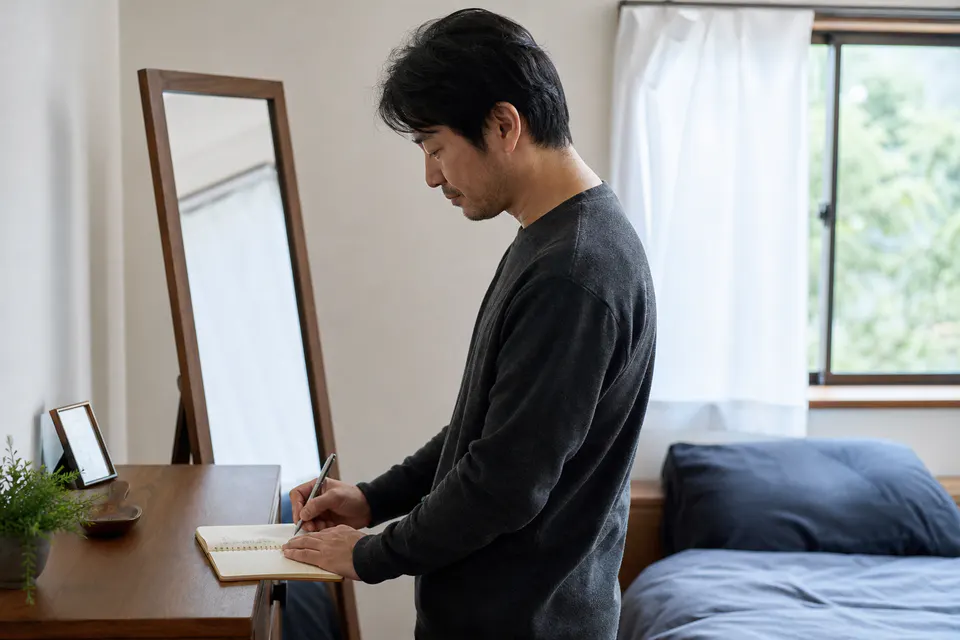 鏡から離れて確認した事実だけをノートに残す男性